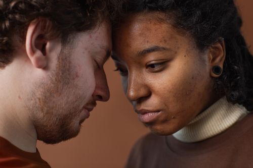Free Close-up of a loving interracial couple gently touching foreheads, expressing connection and emotion. Stock Photo