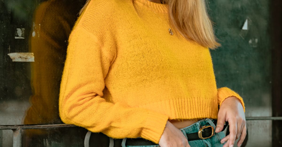 Woman wearing bootcut jeans with a gold knit sweater