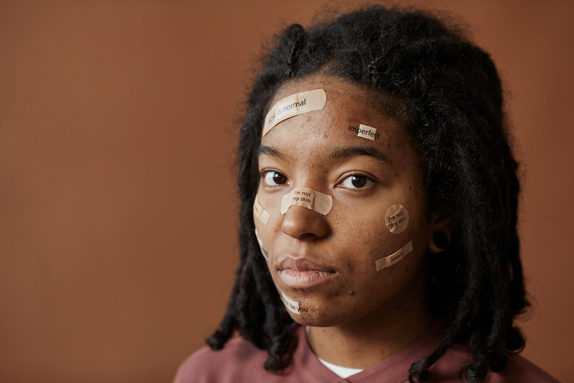 Close-up portrait of a woman with affirming messages on bandages, promoting self-acceptance.