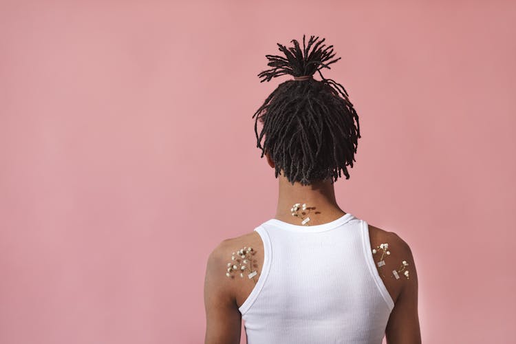 A Person In White Tank Top With Flowers Taped On Skin