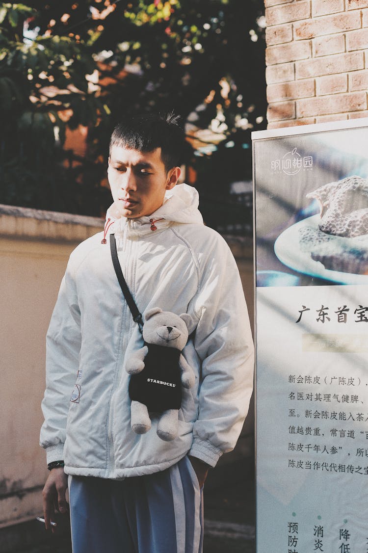 A Man In White Hoodie Jacket With A Bear Cross Body Bag