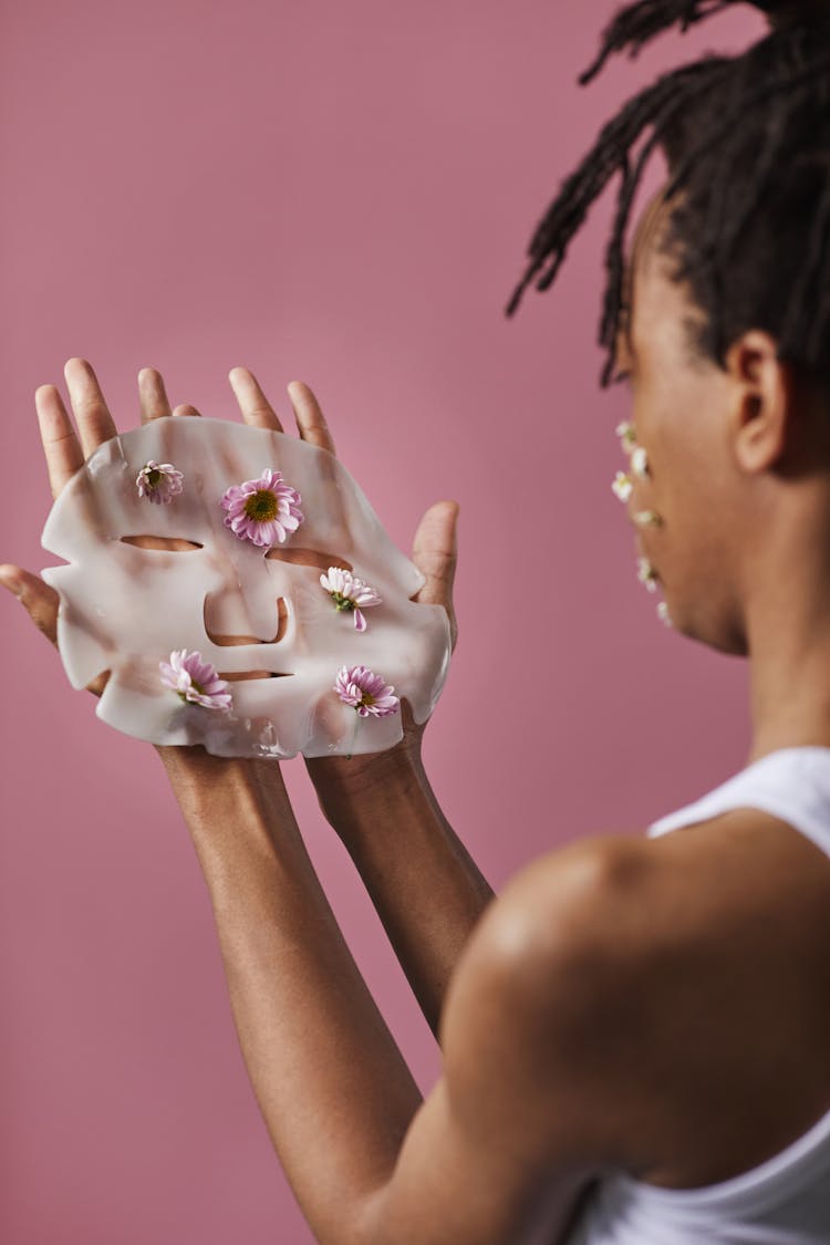 A Person Holding A Cosmetic Face Mask With Flowers