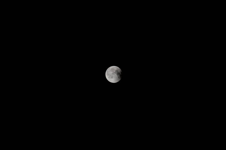 A stunning full moon captured against a dark, starless night sky.