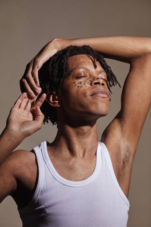 Free Artistic portrait of a young man with dreadlocks and facial marks in a tank top. Stock Photo