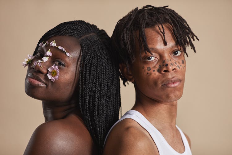 A Man And Woman With Flowers On Face Standing Back To Back