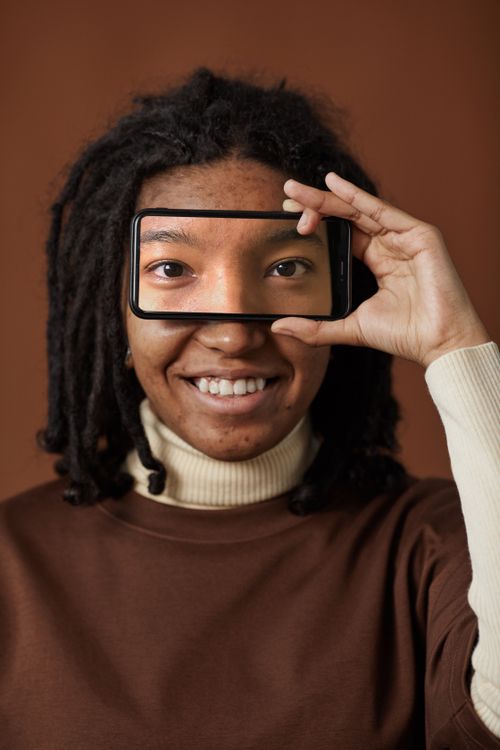 Free A creative portrait of a woman with a smartphone highlighting her eyes in a unique framing style. Stock Photo
