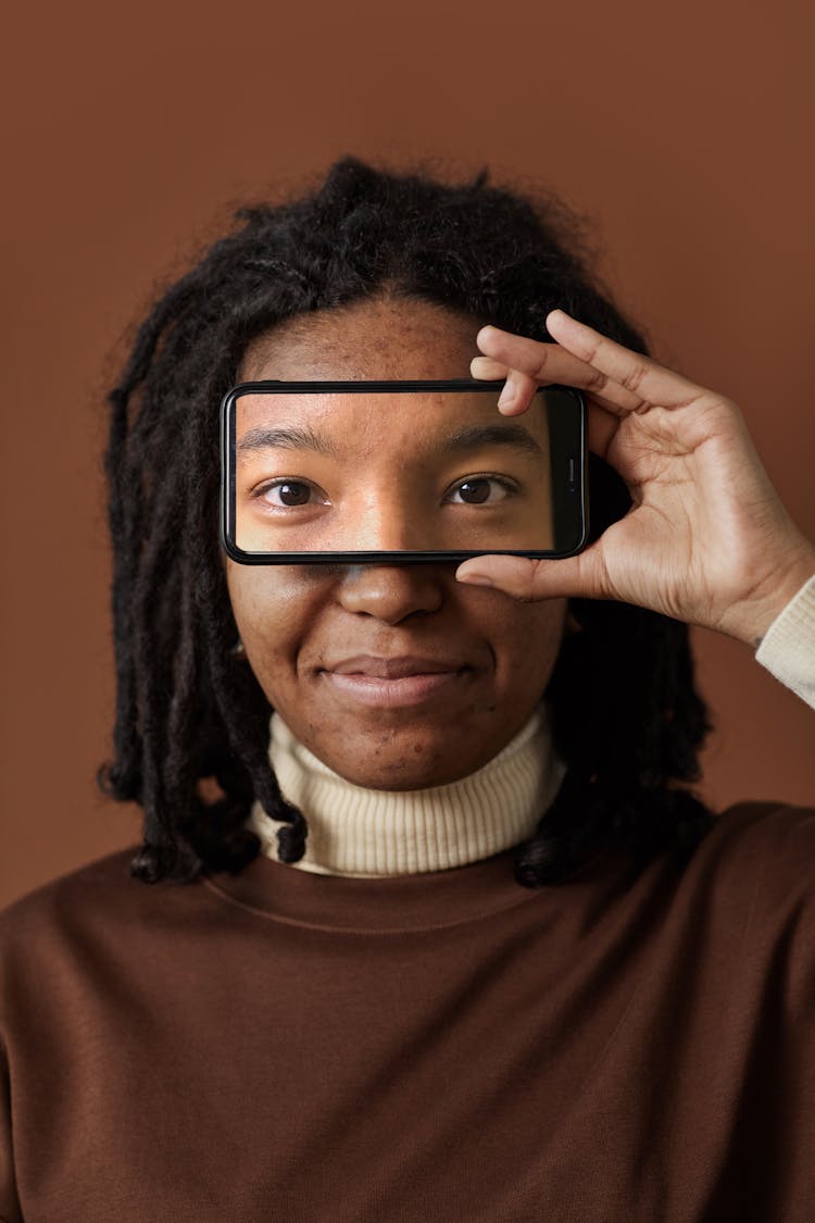 Woman In Turtleneck Sweater Holding A Clear Phone Case Over Her Eyes