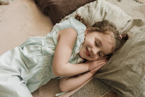 Girl in Green Dress Lying on Brown Textile