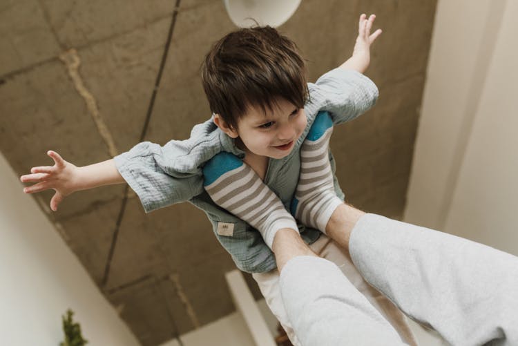 A Person Lifting A Boy With Feet