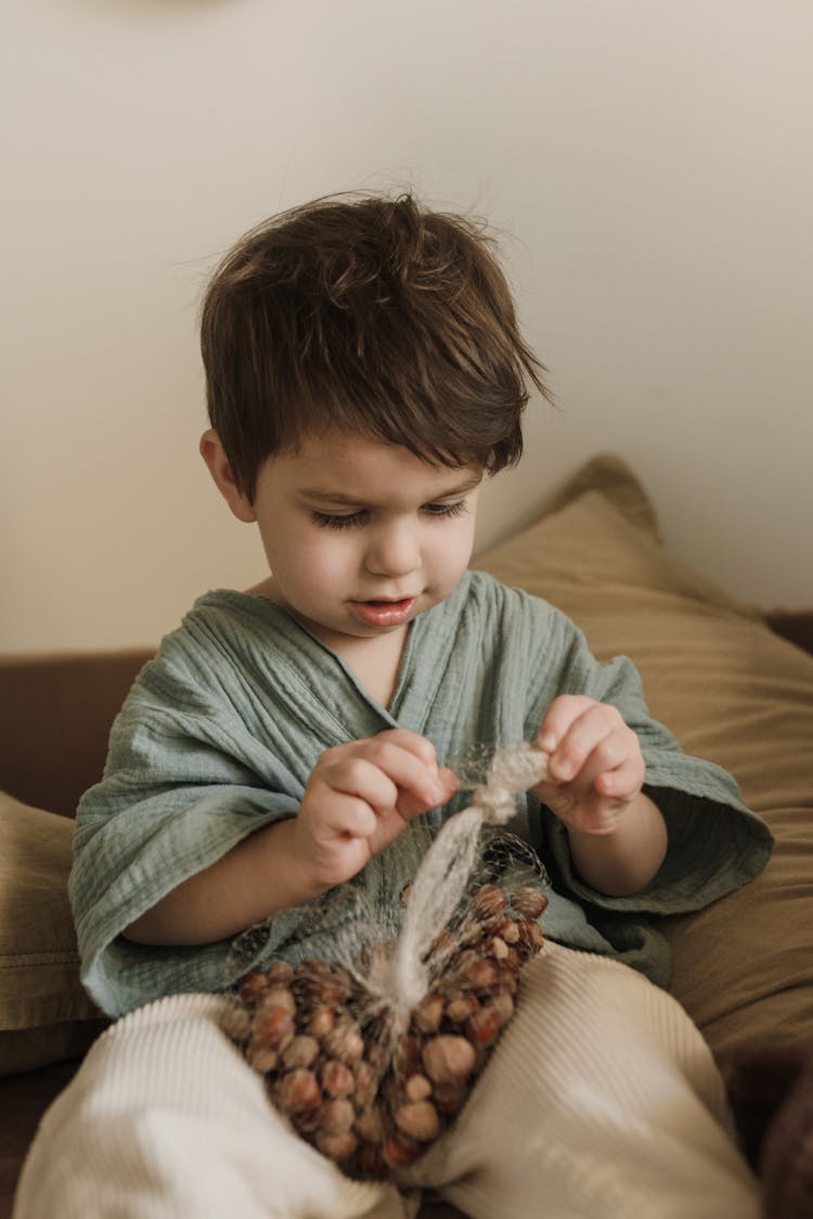 A Boy  Opening Up A Net Full Of Nuts