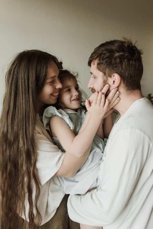 Free A cheerful family moment with parents and child embracing indoors. Stock Photo