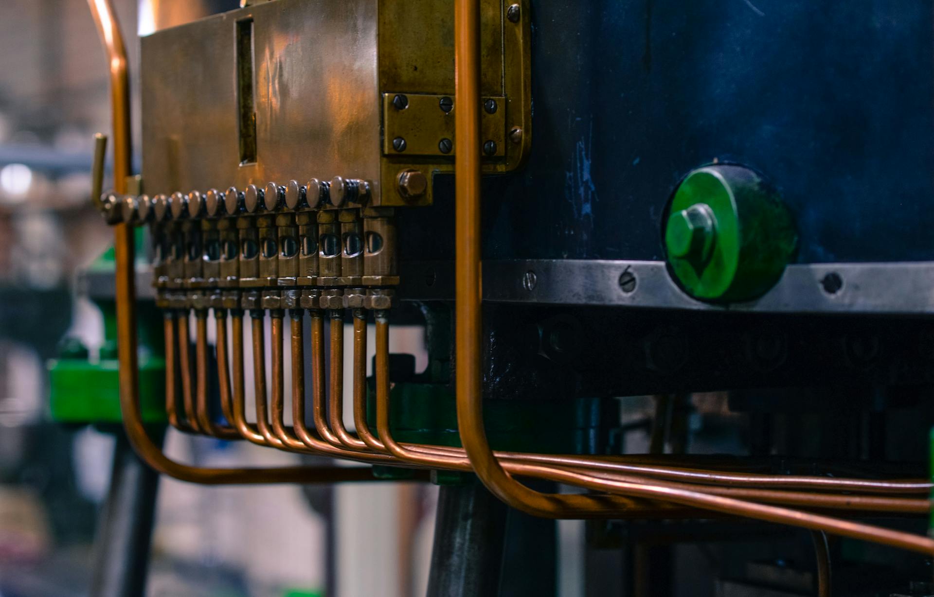 Detailed view of industrial machinery featuring copper tubing and steel components in a factory setting.