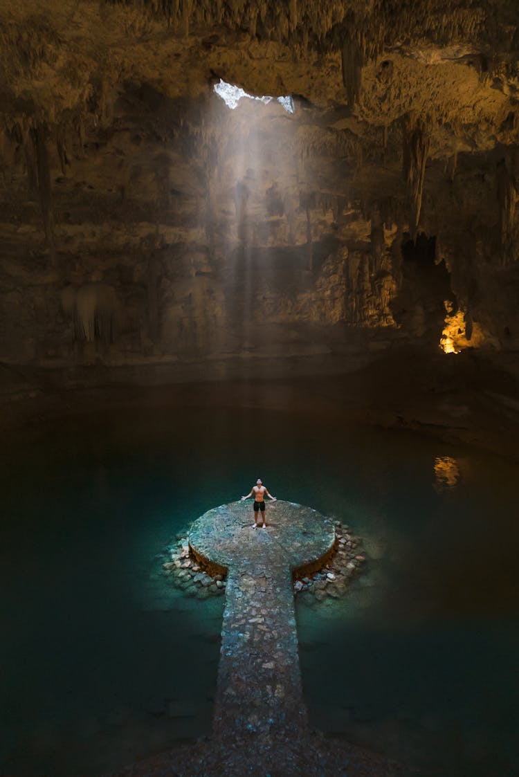 A Man Standing In The Middle Of The Cave Surrounded With Water