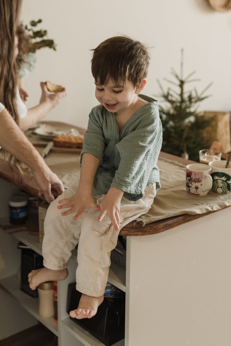 Little Boy Sitting On A Wooden Counter