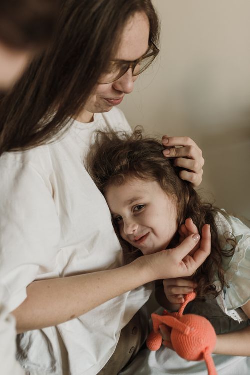 Free A loving mother embraces her smiling daughter indoors, creating a warm family moment. Stock Photo