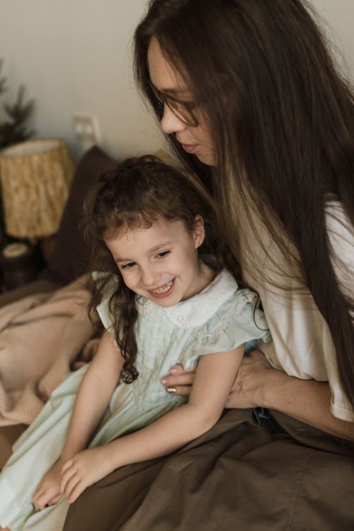 Free A heartwarming scene of a mother and daughter smiling together indoors, showcasing love and togetherness. Stock Photo