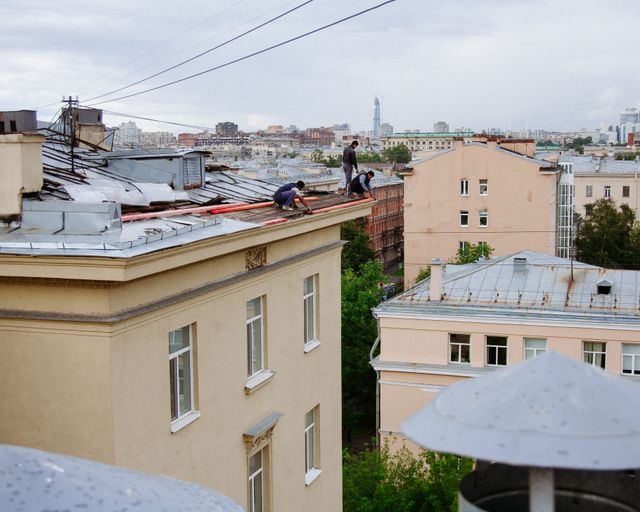 Rooftop repair in the city Construction workers repairing a building rooftop in a city