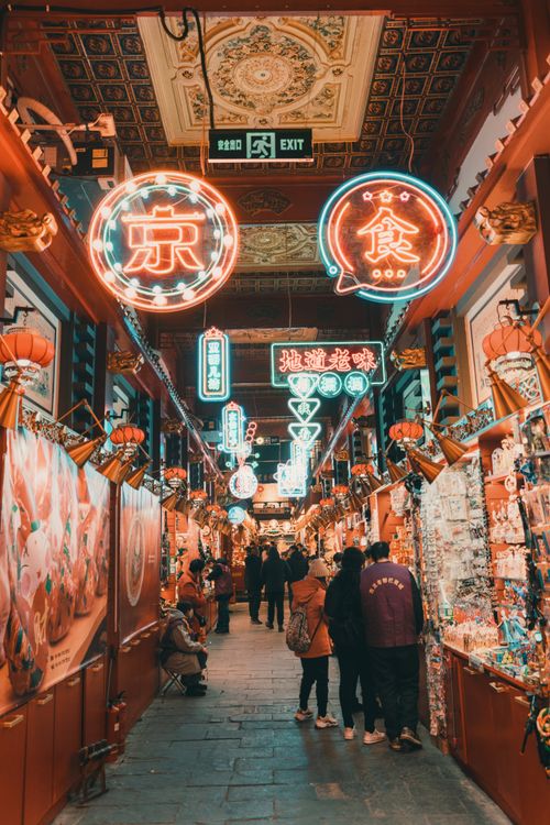 Free Colorful neon-lit alley in an Asian street market at night with people shopping. Stock Photo