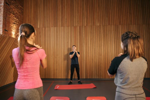Fitness instructor leading a training session with two women in a modern gym setting.