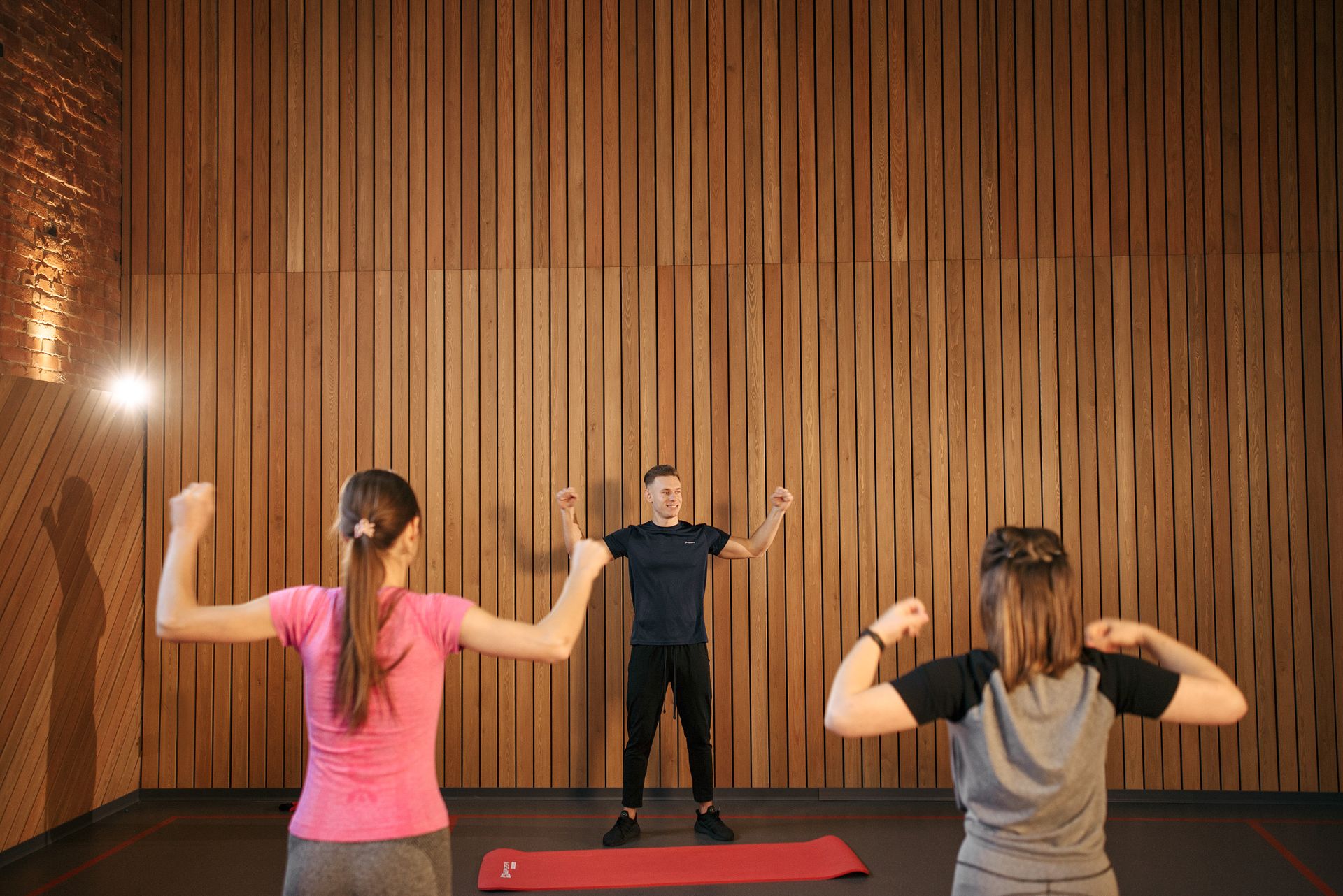 Fitness instructor assists two women during a workout in the studio