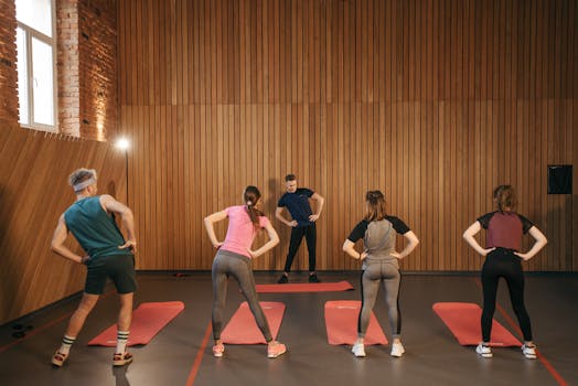 People stretching on yoga mats during a fitness class indoors.