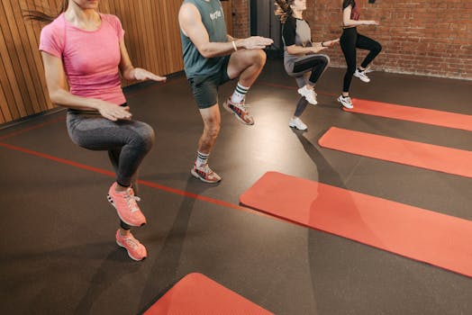 A group performs high knees together in an indoor fitness studio with yoga mats.