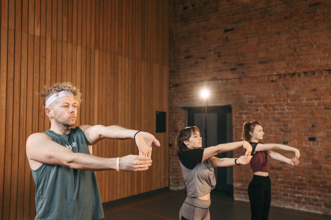 A trainer guiding people through gentle stretching in a bright studio