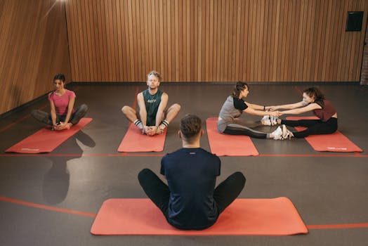 People engaging in a yoga class with red mats in an indoor wooden studio.