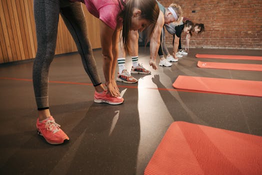 A diverse group stretches on red mats in a gym setting, enhancing fitness.