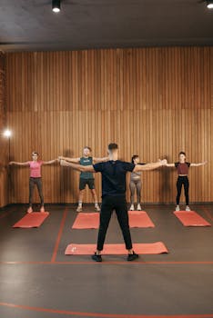 People participating in a group exercise class in a gym environment.