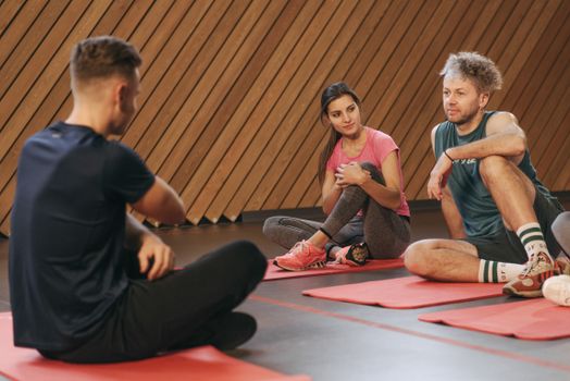 Active yoga class with adults on mats in a modern indoor setting.