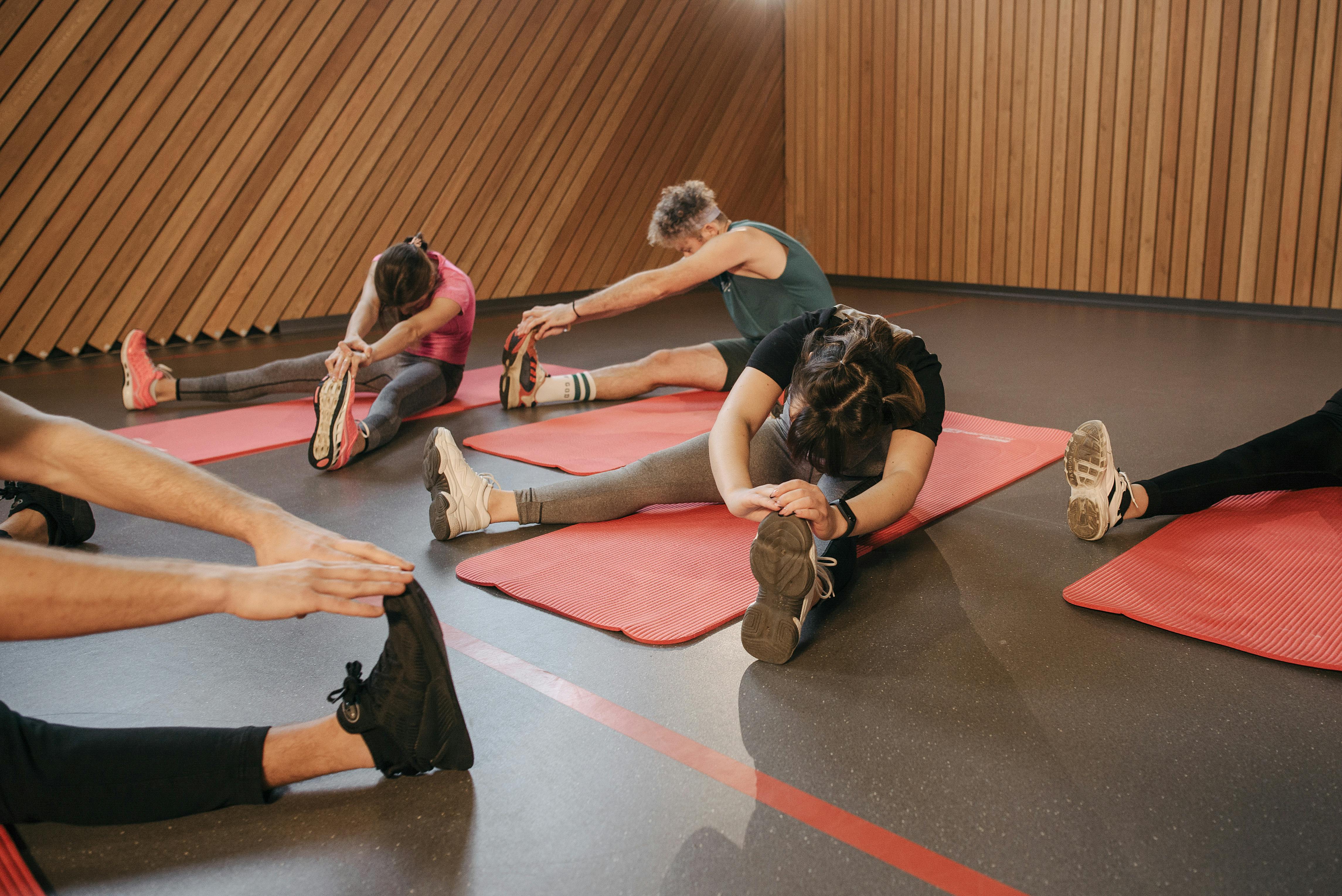 People stretching on exercise mats in an indoor gym during a workout session.