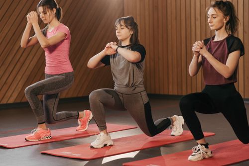 Free Three women performing lunges in a gym setting, promoting fitness and an active lifestyle. Stock Photo