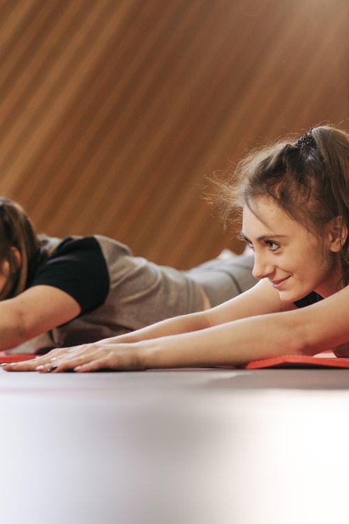 Free Two women happily stretching on mats in a bright, cozy studio setting. Stock Photo