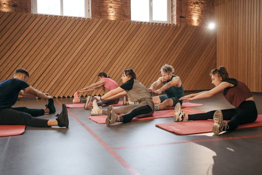 Group of adults stretching on mats in a modern gym setting, promoting healthy lifestyle.