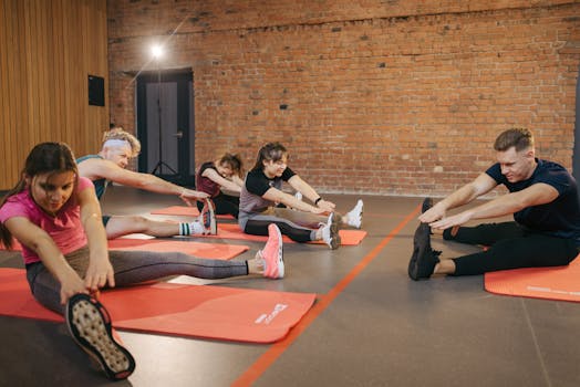 A group of diverse adults stretching on mats in a brick-walled fitness studio.