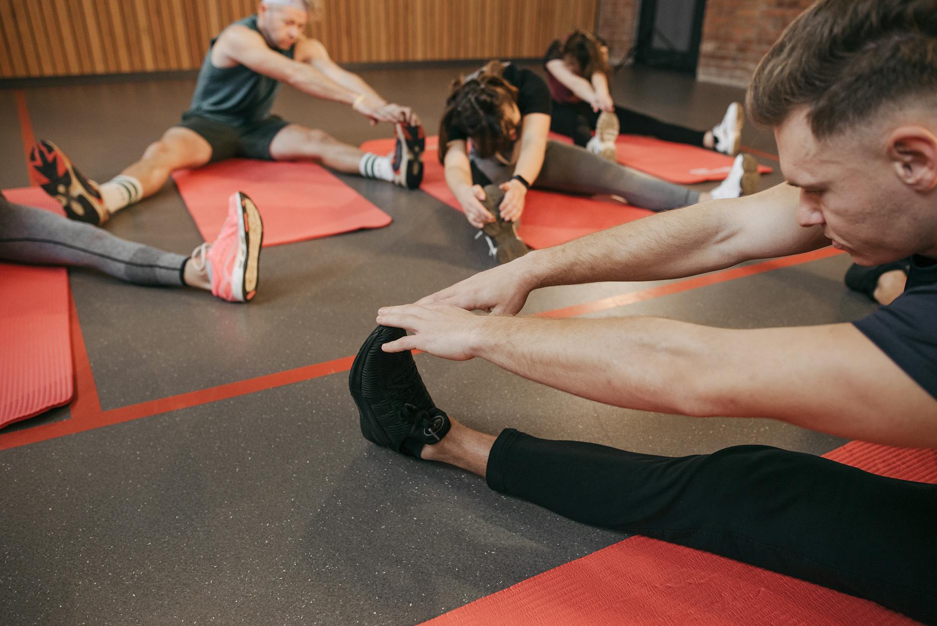 https://www.pexels.com/photo/people-sitting-on-a-yoga-mat-while-stretching-their-legs-6339464/