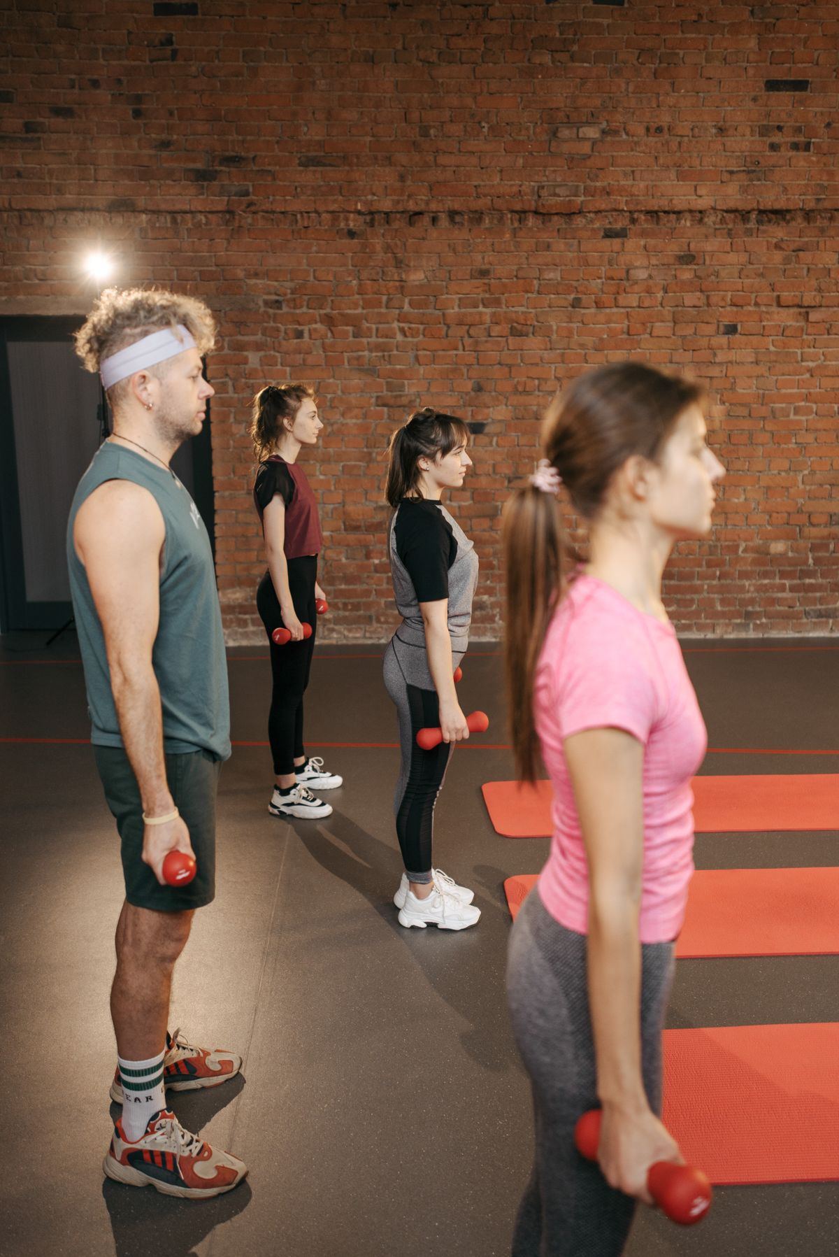 Fitness group holding dumbbells together in an indoor gym