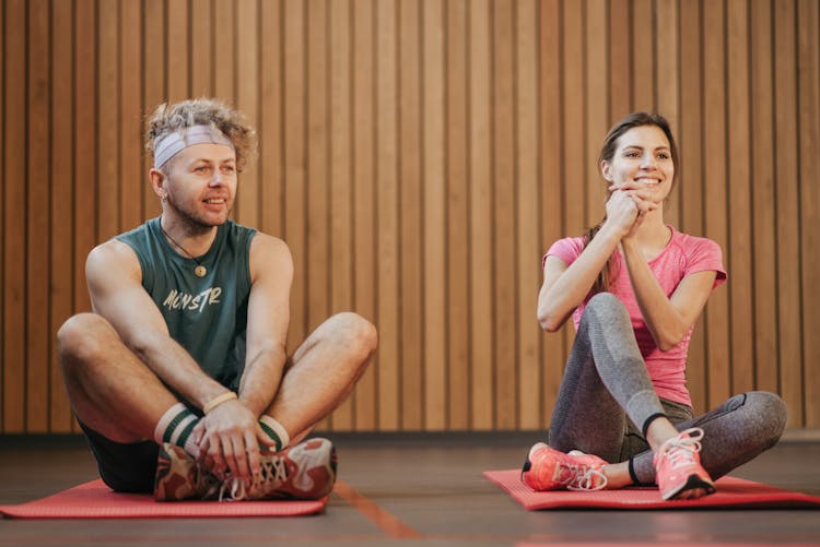 A Man And A Woman Sitting On Mats 