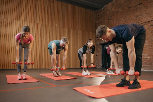 Adults exercising in an indoor fitness class with dumbbells and yoga mats for healthy lifestyle.