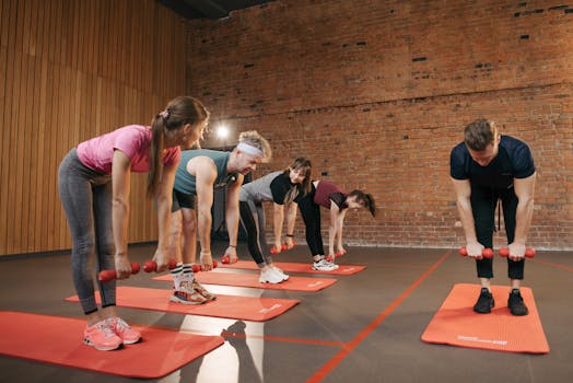 Fitness group performing exercises with dumbbells in a modern yoga studio setting.