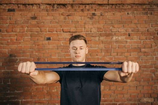 Man using resistance band against brick wall for fitness exercise.