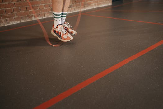 Feet of a person in sneakers skipping rope on an indoor gym floor.