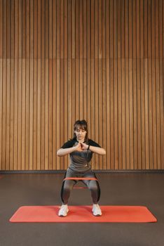 A woman exercising with a resistance band in a gym setting, focusing on strength training.