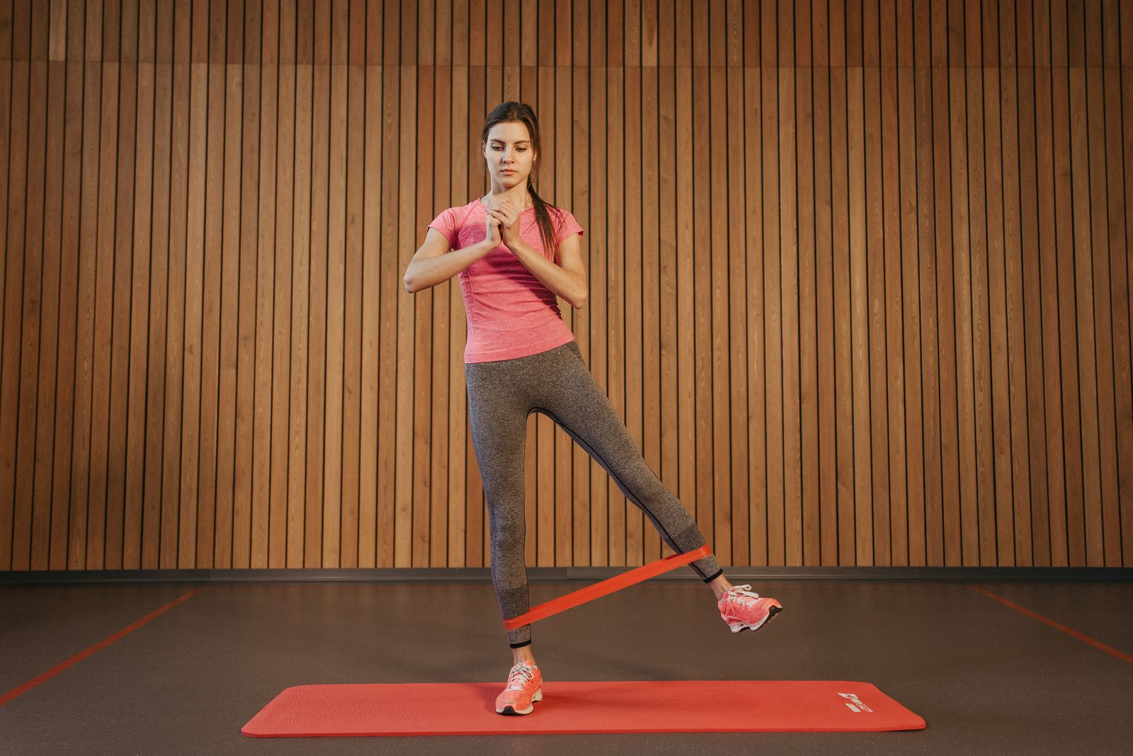 Woman performing a resistance-band leg exercise in a gym