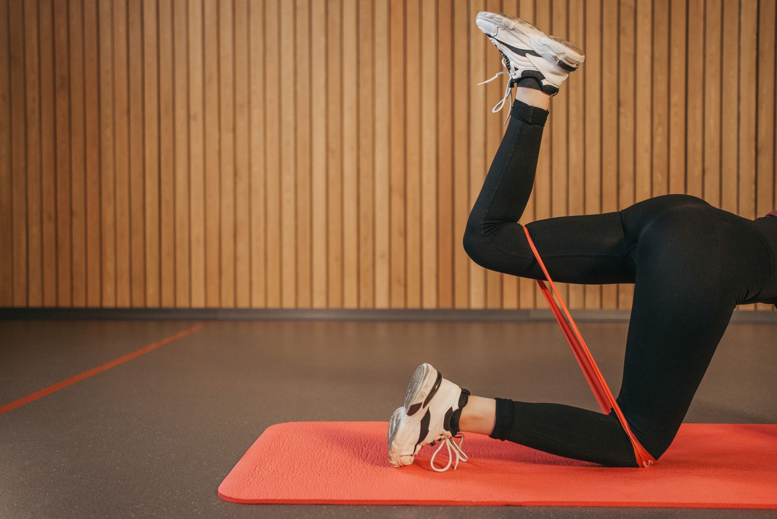 Woman performing a resistance-band leg exercise on a mat