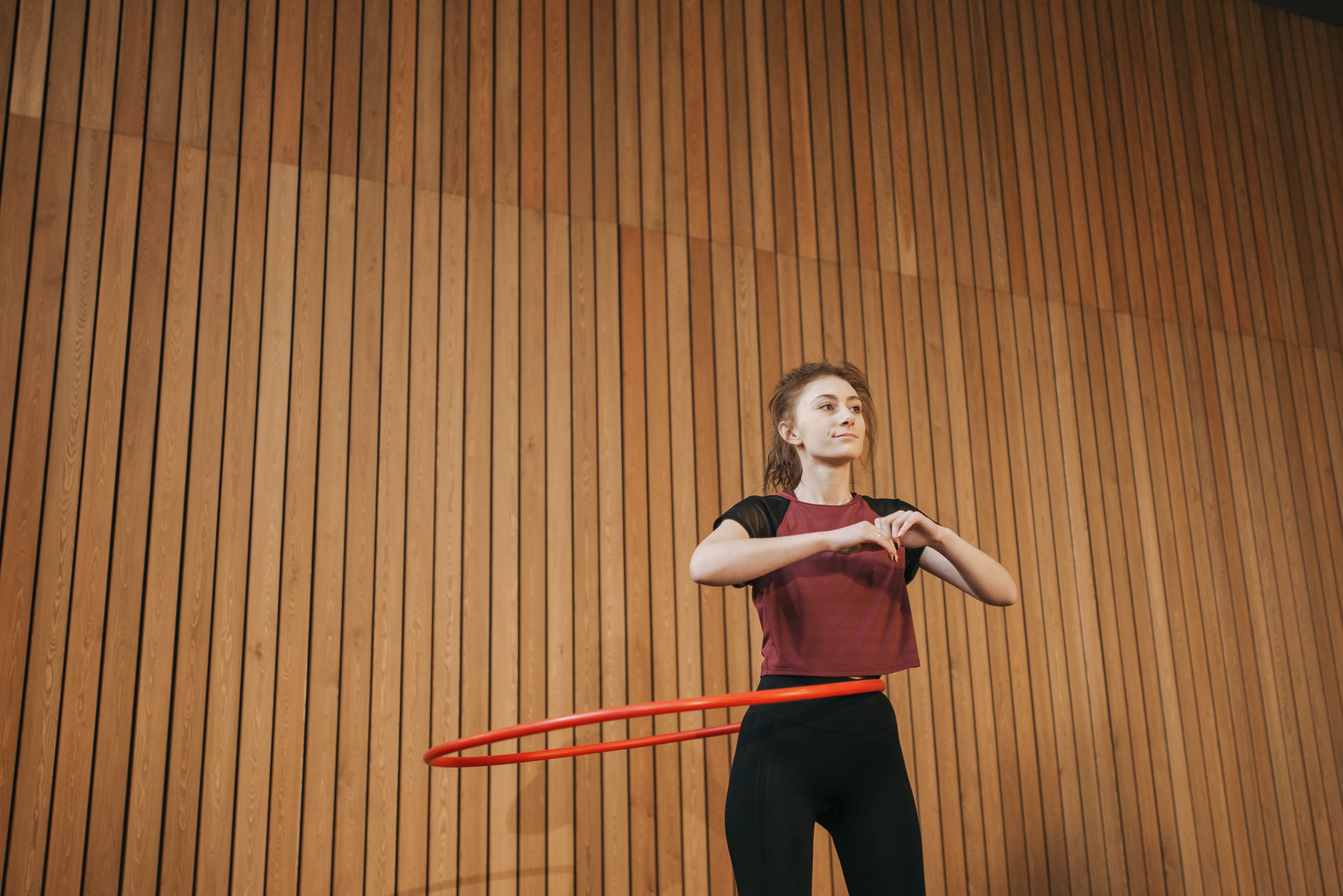 Woman spinning a classic weighted fitness hoop around her waist in an indoor studio