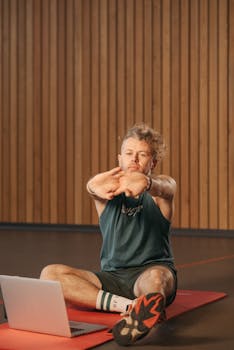 Adult man stretching on a yoga mat indoors, focusing on fitness and health.