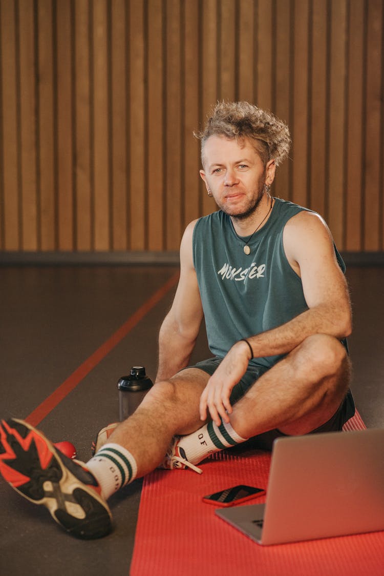 Man Sitting On Yoga Mat In Front Of Laptop