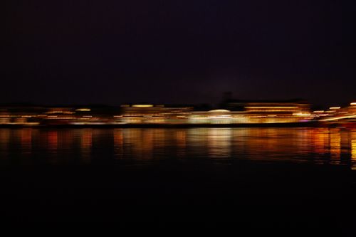 Free A vibrant, blurred cityscape with illuminated reflections over water at night. Stock Photo